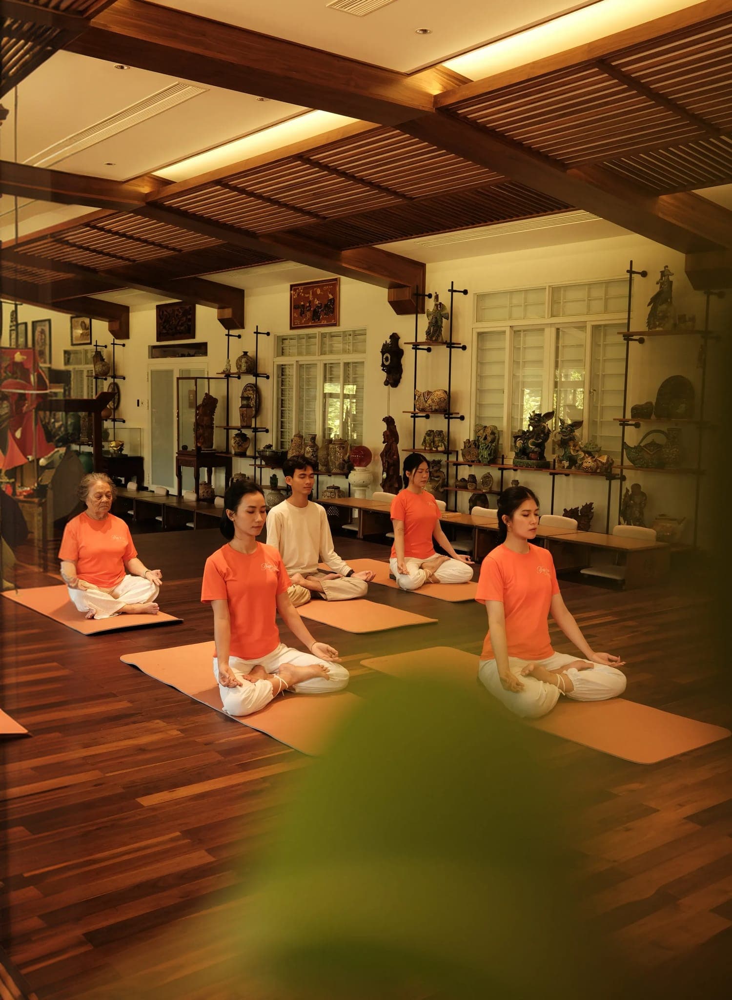 Lớp yoga thiền trong không gian ấm áp với học viên và nền gỗ