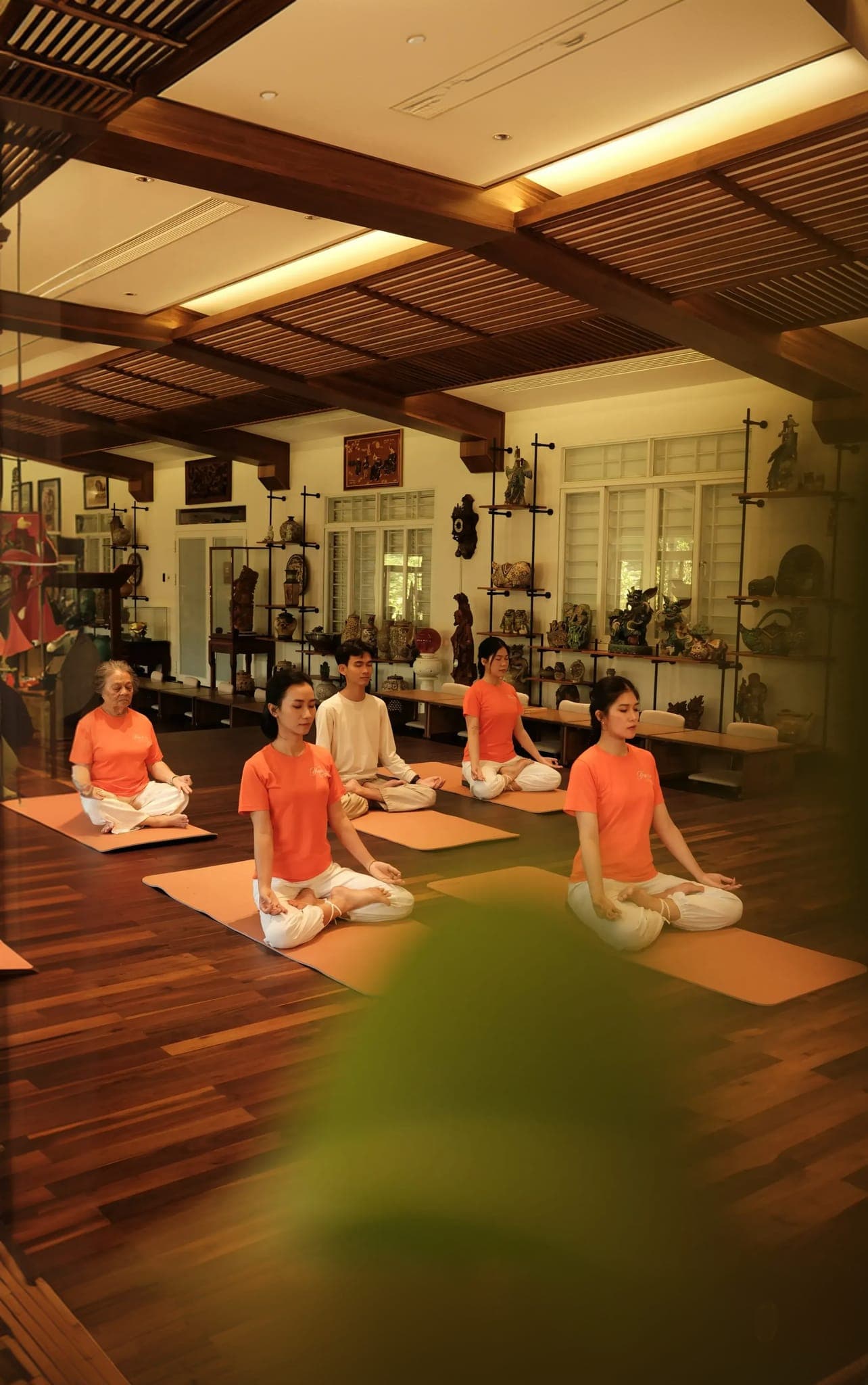 Lớp yoga thiền trong không gian ấm áp với học viên và nền gỗ